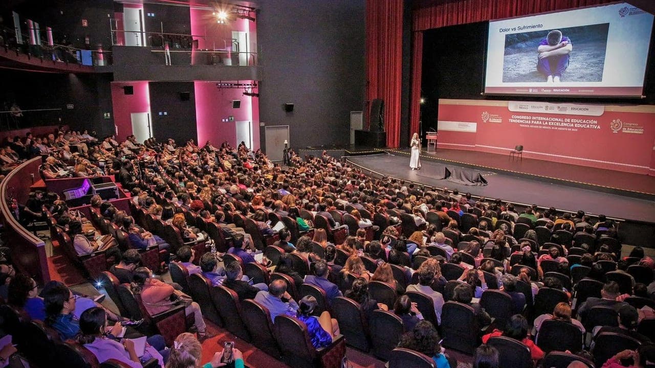 Mónica Esgueva speaking on stage to a full auditorium